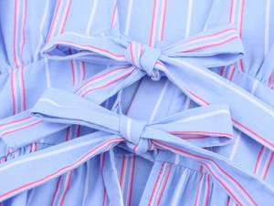 Detail of blue striped shirt showing decorative double bows and cotton fabric texture