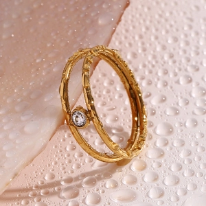 Macro di anello a doppio strato in oro 18K con finitura martellata e zircone tra gocce d'acqua