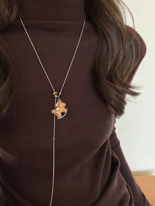Detail of wooden rocking horse pendant with tiger eye stone on a pearl Y-necklace