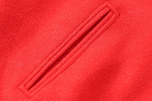 Close-up of a red wool bomber jacket welt pocket showing premium fabric and stitching