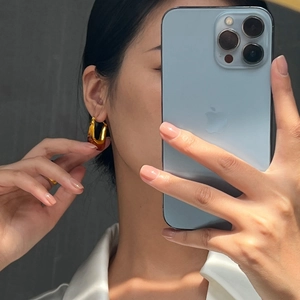 Retro U-shaped resin earrings in amber and gold worn by a model in a natural mirror selfie