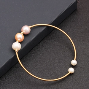 Close-up of gold coil bracelet featuring mixed pink and white freshwater pearls