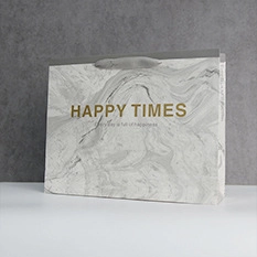 Detail of grey marble paper gift bag with golden Happy Times text and rope handle