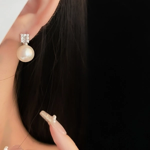 Detailed close-up of a model wearing a zircon-studded cream pearl earring with gold plating