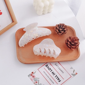 Elegant white iridescent hair claw clips set in a warm lifestyle aesthetic setting