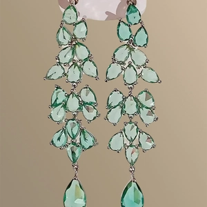 Detail of light green teardrop crystal drop earrings with layered silver tassel design