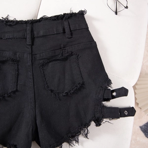 Primer plano de pantalones cortos negros de talle alto con hebillas metálicas y bajos deshilachados