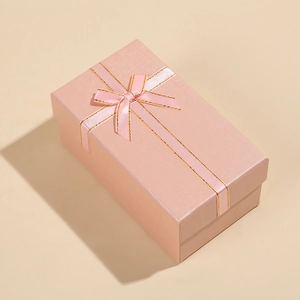 Angled view of a rectangular pink jewelry gift box with a gold-edged ribbon bow