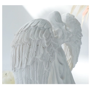 Close-up of white angel statue showing detailed wing textures and praying pose
