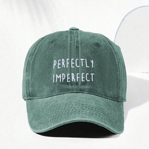 Detail shot of Perfectly Imperfect white embroidery on a dark green cotton baseball cap
