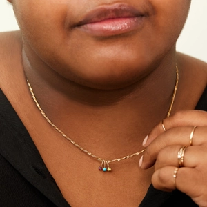 Close-up of golden birthstone necklace with colorful zircon pendants on a model