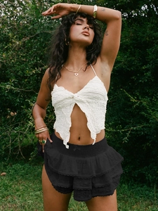 Détail d'un top licou blanc associé à une jupe noire à dentelle multicouche sur mannequin extérieur