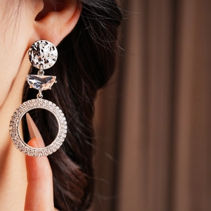 Macro shot of silver crescent moon earrings with cubic zirconia worn by a model