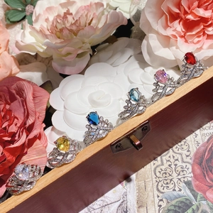 Close-up of elegant crown rings with multi-color pear-cut zircon on a wooden box
