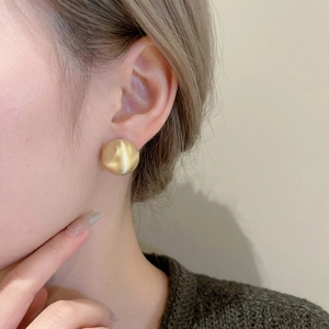 Minimalist matte gold round geometric earrings for women in a stylish professional close-up