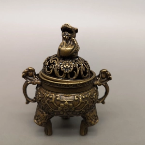 Macro shot of an antique bronze censer with a mythical beast lid and hollow floral patterns