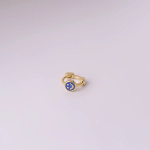 Mini gold-plated smiley face earring with blue enamel charm on a light purple background