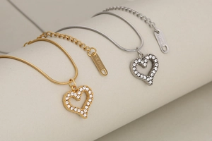 Macro detail of gold and silver heart pendants with sparkling pavé crystals and snake chains