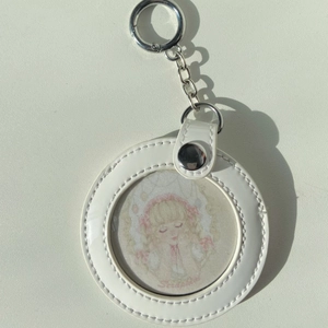 Gedetailleerd zicht op de ronde witte kunstlederen sleutelhanger met zilveren metalen ring