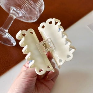 Elegant cream white acetate hair claw clip with heart-shaped cutout pattern and metal spring