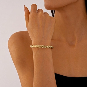 Close-up of golden twisted rope cuff bracelet on woman's wrist in minimalist setting