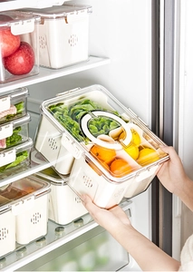 Close-up of clear fridge organizer with drainage basket holding fresh lemons and oranges