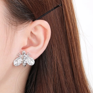 Close-up of a silver stainless steel bee earring worn by a model for a detailed look