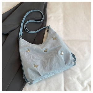 Detail of light blue pleated nylon shoulder bag with decorative metal butterfly charms