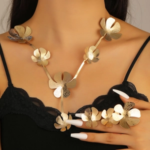Close-up of a luxury gold flower jewelry set with textured petals on a model