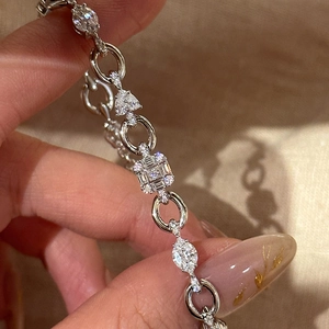 Macro view of a silver-tone zircon bracelet with heart and marquise charms on a hand