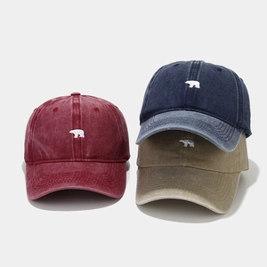 Close-up of vintage washed baseball caps featuring bear embroidery and cotton texture
