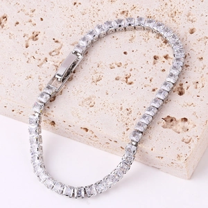 Macro shot of silver-tone bracelet with square-cut clear zircons on stone surface