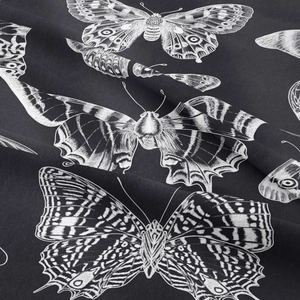 Detailed macro shot of white butterfly patterns on black fabric background texture
