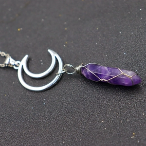 Close-up of a purple hexagonal amethyst pendant with silver double moon wire wrap detail