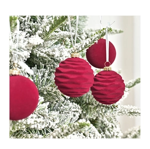 Detail of burgundy velvet Christmas balls with ribbed texture on a snowy tree
