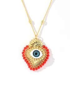 Detail of 18k gold heart pendant with evil eye design and red beads on chain