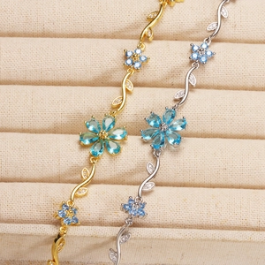 Detailed view of vine-style bracelets with blue gems and crystal flower petals