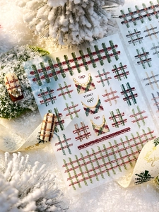 Macro shot of British style red and green plaid embossed nail stickers on snow background