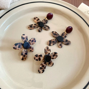Close-up of leopard print flower earrings on a ceramic tray in vintage warm lighting