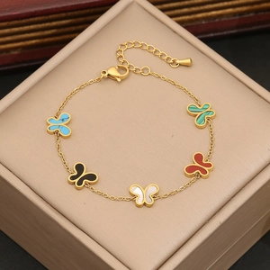 Bracelet chaîne dorée orné de cinq pendentifs papillon colorés sur un coffret bijoux