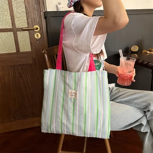 Dettaglio della borsa tote in tela seersucker a righe con tracolla rosa e logo