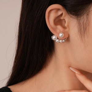 Asymmetric pearl and diamond ear jacket studs in silver finish on a female model