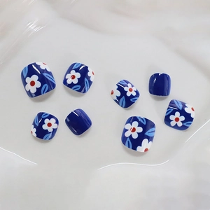 Blue square press-on toenails with white floral designs on elegant white silk background