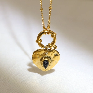Detail of 18K gold heart pendant with hammered texture and black drop-shaped gemstone