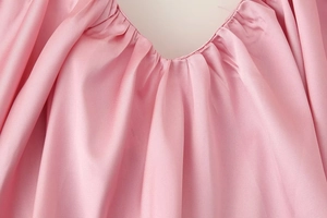 Dettaglio dello scollo a V con pieghe su un elegante abito sottoveste in raso rosa