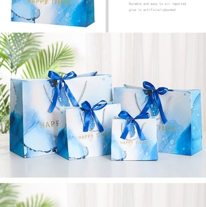 Close-up of blue marble gift bags with gold Happy Times text and silk ribbon handles