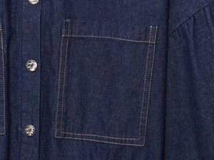 Detail of dark blue denim shirt featuring contrast yellow stitching and metallic buttons