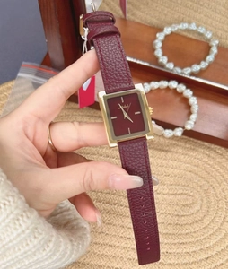 Close-up of vintage rectangular red leather strap watch with polished gold case finish