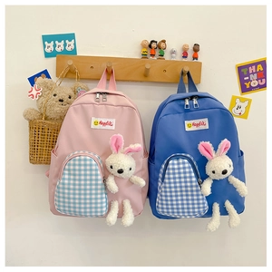 Detail view of cute kids backpacks with blue plaid pockets and plush bunny pendants