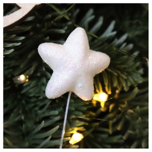 Close-up of white glitter star Christmas tree topper on pine branch with warm lights